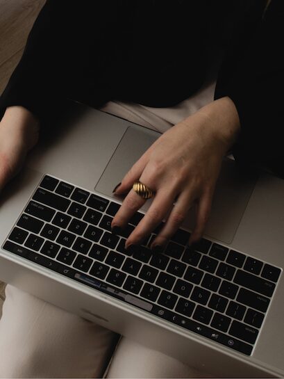 Female solopreneur typing on a MacBook while working on her email list.